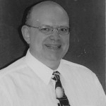 Black and white headshot for Rick Bragg. White male bald and wearing glasses.