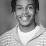 Black and white headshot for Justin McCoy. Black male with short black hair.