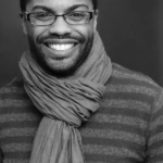 Headshot for Harrison David Rivers. Black male with a goatee who is wearing glasses.