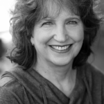 Black and white headshot for Nancy Riggs. Caucasian female with short wavy hair.